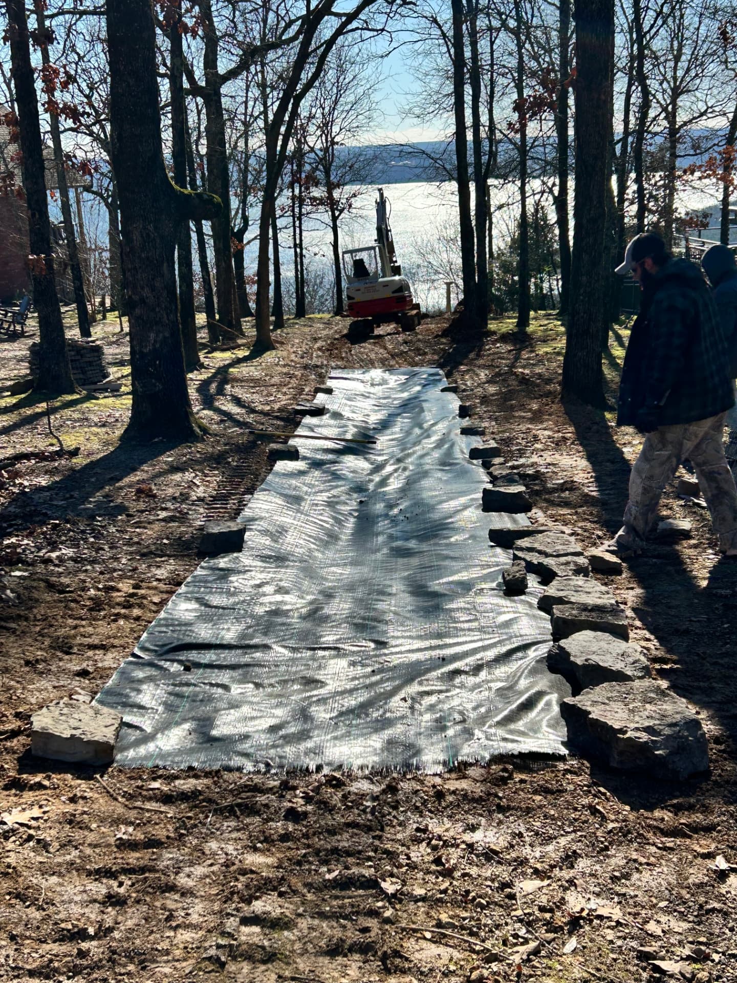 Filter fabric laid in a graded trench with a mini excavator before stone drainage work near Greers Ferry Lake