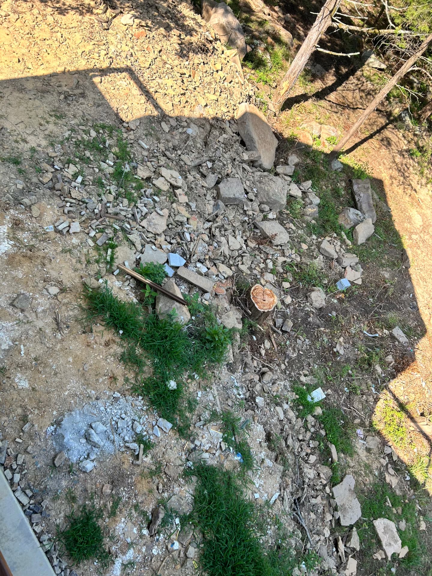 Rocky, eroded hillside covered in construction rubble and stumps before landscaping in Heber Springs, Arkansas