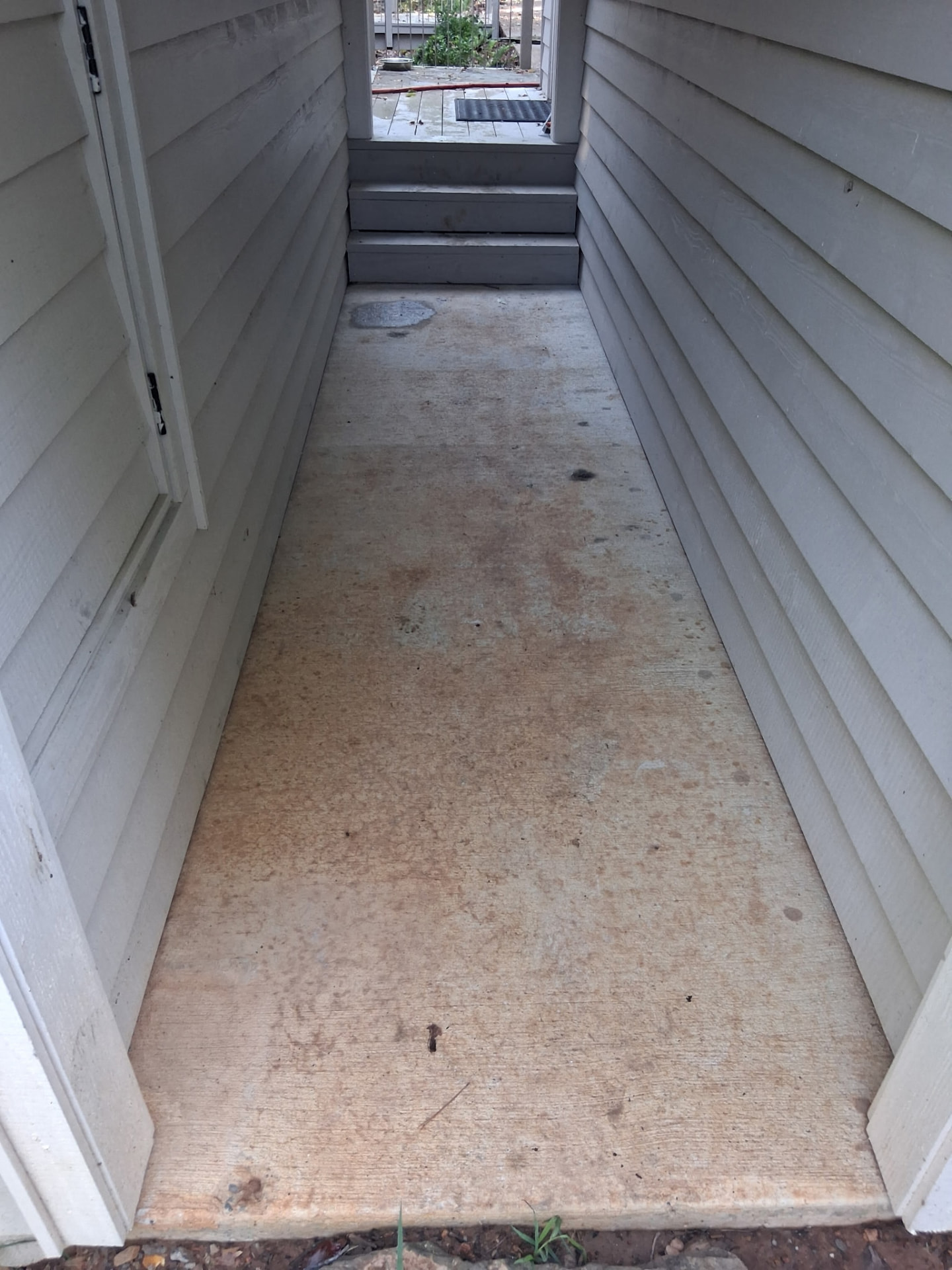 Narrow stained concrete walkway between two house walls before flagstone installation in Greers Ferry, Arkansas