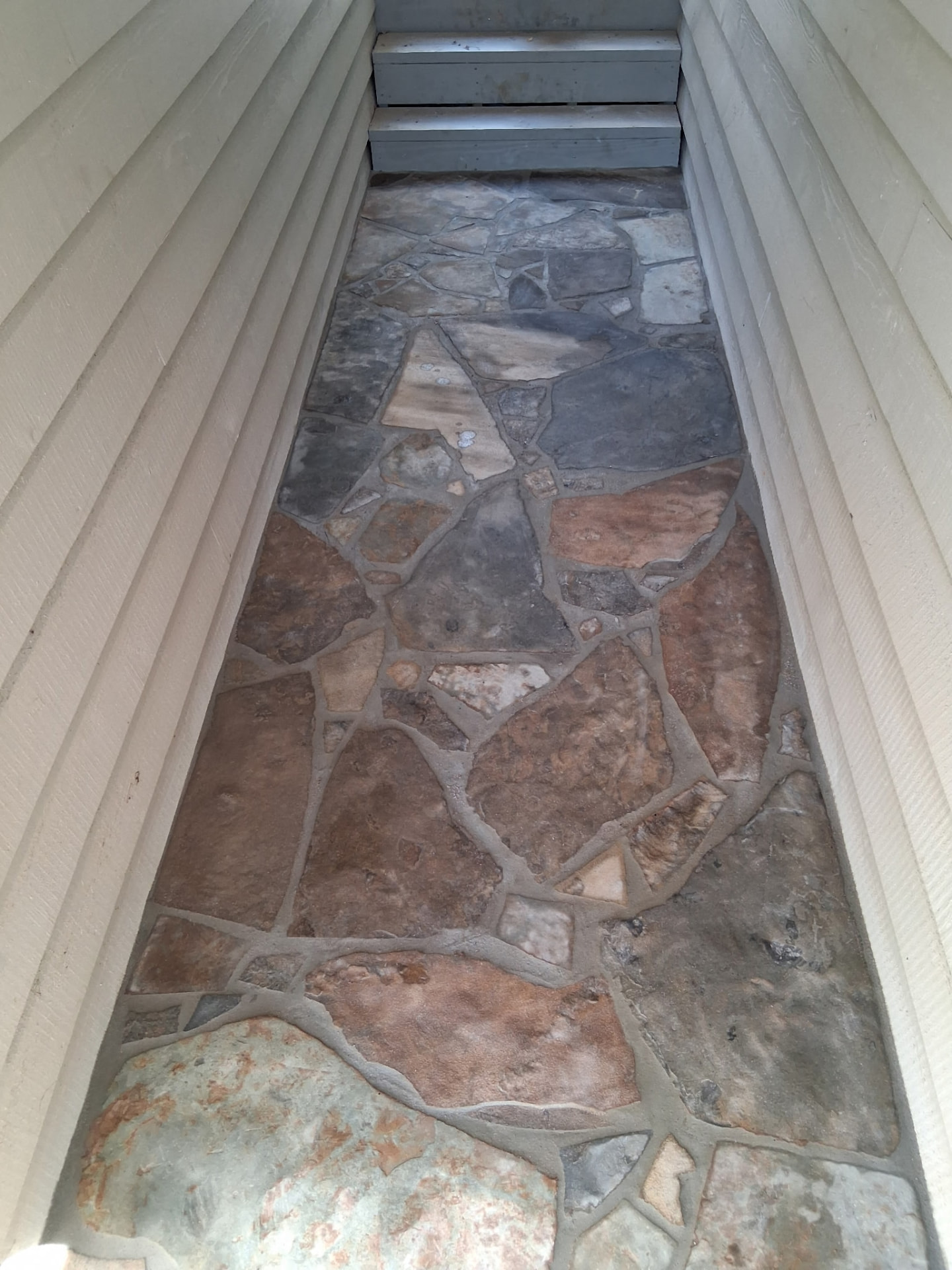 Finished irregular flagstone walkway between two house walls in Greers Ferry, Arkansas